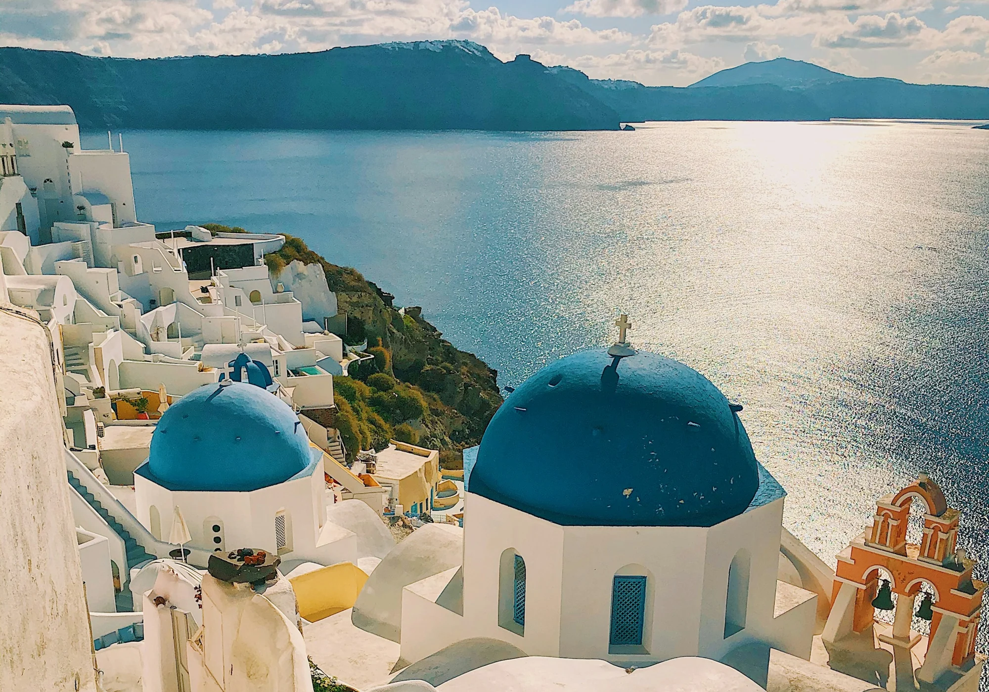 Sunlit white architecture and blue domes overlooking the Aegean Sea in Santorini